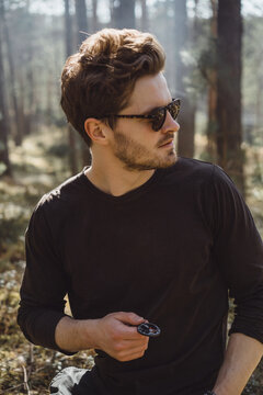 Man in the forest on a hike uses a compass, is looking for a way