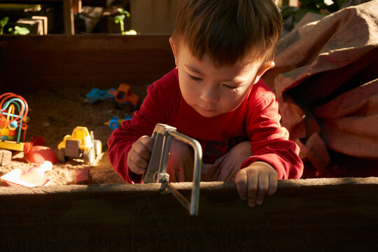 boy sitting and sawing a board