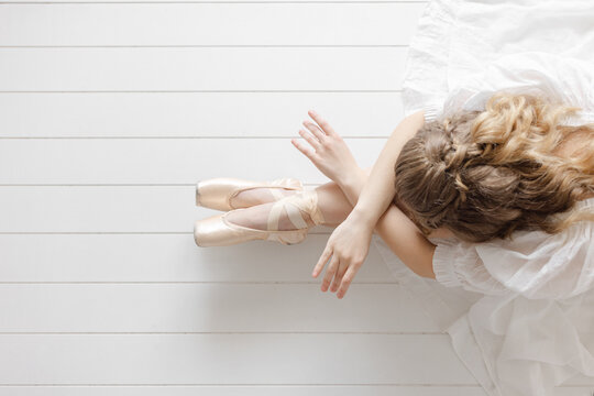 ballerina poses on ground in white studio croise en pointe