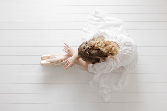 ballerina poses on ground in white studio croise en pointe