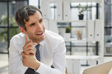 Image of successful businessman 30s thinking and holding index finger at forehead