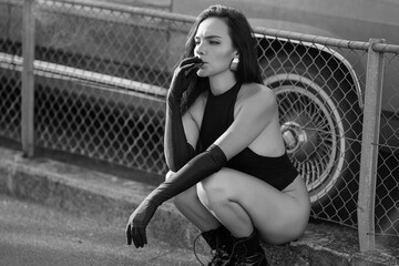 Beautiful sexy women vaping outdoor. Fashion model sitting near retro car and smokes electronic...