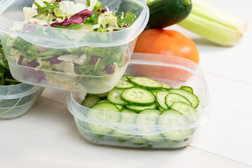 Chopped salad, vegetables and herbs in a plastic container. Storing food for freezing