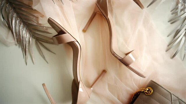 A beige pair of strappy heels near a bag on a piece of tulle