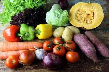 Variety of fresh vegetables including bell peppers, carrots, tomatoes, and pumpkin on a table