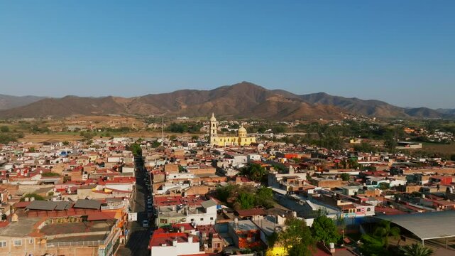 Dolly in aerial over the city of Tamazula fastly approaches the Diocesan sanctuary church, drone flies between the bell towers