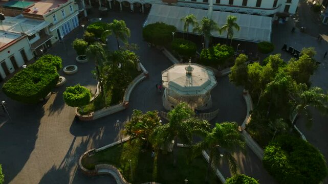 Orbit top-down view of Kiosko in Tamazula main plaza city park with trees and buildings