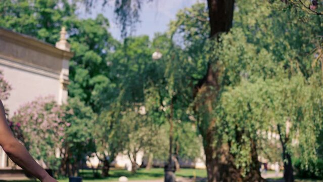 outdoors in a park with trees young handsome brunette guy in jeans and a white T-shirt, a brunette stuffing a shuttlecock warming up before playing bambinton
