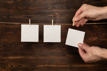 Obraz premium man hand take paper note cards hanging with wooden clip or clothespin on rope string peg on wooden background