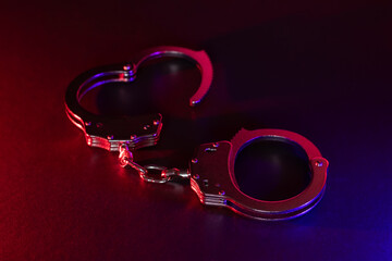 Silhouette of handcuffs. Image with the flashing red and blue police lights dark background.