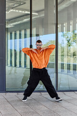 A young European guy dressed in loose clothes dances a modern electro dance