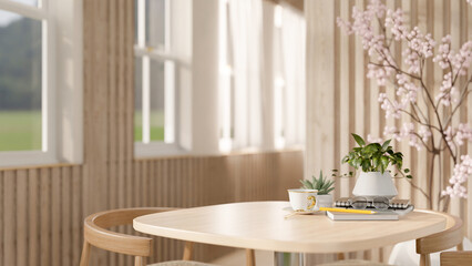 A wooden table by the window with stationery and decor in a contemporary minimalist room.