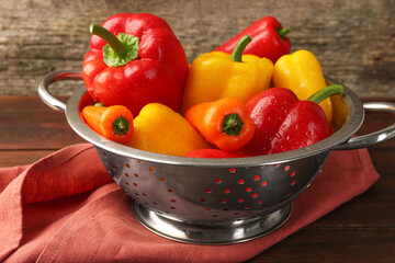 Metal colander with fresh peppers on table, closeup