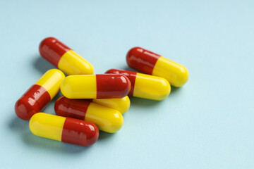 Many antibiotic pills on light blue background, closeup