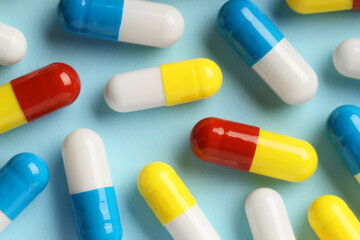 Many antibiotic pills on light blue background, top view