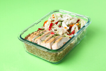 Healthy meal. Fresh salad, chicken and buckwheat in glass container on green background