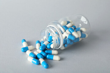 Scattered antibiotic pills and bottle on grey background. Medicinal treatment