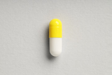 One antibiotic pill on grey background, top view. Medicinal treatment