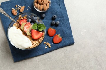 Tasty granola with berries, yogurt and mint on grey table, top view. Space for text