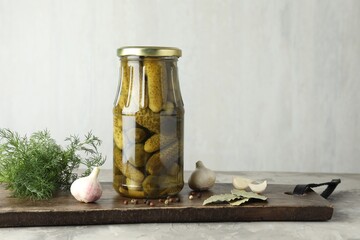 Pickled cucumbers in jar and spices on grey table. Space for text