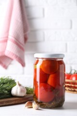 Tasty pickled tomatoes in jar, garlic and dill on white table