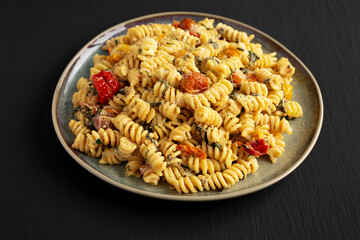 Homemade Baked Boursin Pasta on a Plate on a black background, side view.