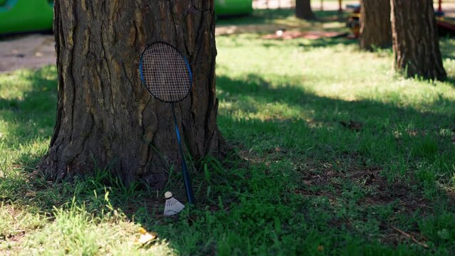 on the street in the park on the green mown grass stand near the tree a white shuttlecock racket for playing bambinton element of sport