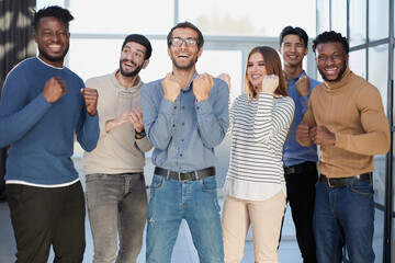 Fototapeta premium Group of happy managers rejoice at a successful deal by clenching their hands into fists and raising them up