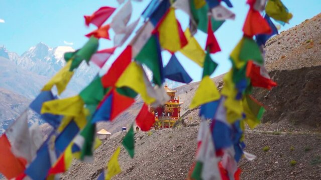 Closeup shot of Gue Monastery with defocused prayer flags waving in front of it as seen on the way towards Spiti Valley in Himachal Pradesh, India. Selective focus on the Gompa behind the prayer flags