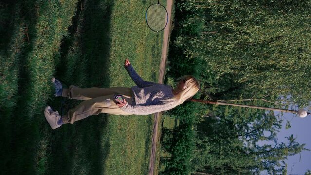 vertical video on the street in the park among the trees young brunette guy with a blonde is juggling rackets for playing bambinton