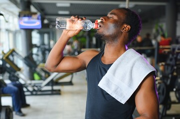 African american bodybuilder holding mug with water at modern gym