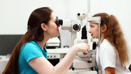 A little patient undergoes an eye test by a professional optometrist using modern diagnostic...