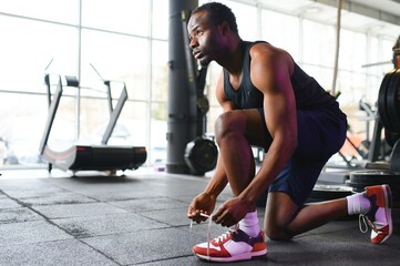 Sportsman tying shoelaces, ready for workout in gym, free space