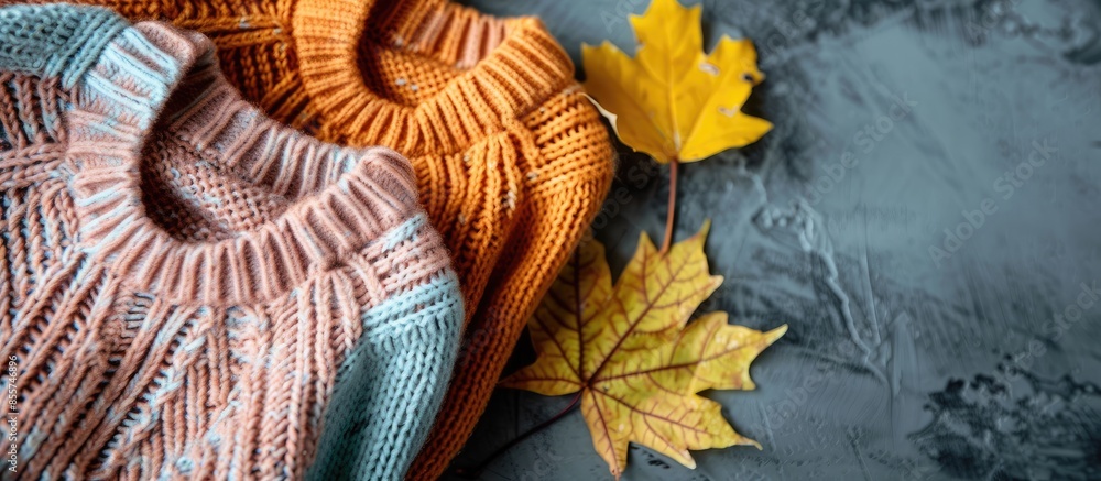 Poster Autumn composition with cozy knitted sweaters in pastel shades and a dry leaf. with copy space image. Place for adding text or design