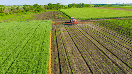 Aerial view on tractor as spraying field with sprayer, herbicide and pesticide © Roman_23203
