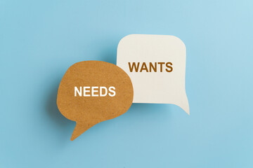 Message WANTS versus NEEDS on real brown and white speech bubble paper cut with blue background, for choice conceptual image