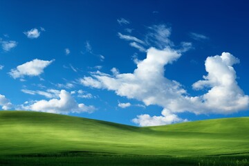 Fototapeta premium A beautiful summer or spring landscape with green grass on the hills and green fields. The blue sky is filled with white clouds and bright sunlight. Nature as a background.