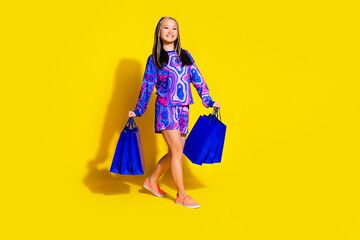 Full length photo of satisfied woman wear print pullover hold shopping bags walk to empty space...