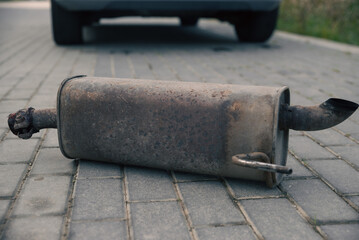the rusty exhaust pipe, the car's muffler has fallen off and is lying on the road