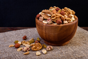 Mixed nuts in wooden bowl on wooden background.