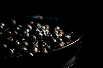 Black currants in a plate on a black background. Berries concept