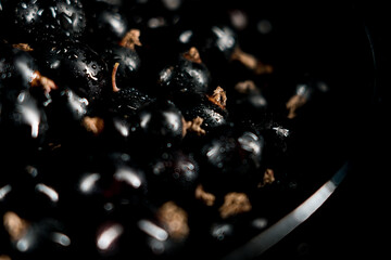 Black currants in a plate on a black background. Berries concept