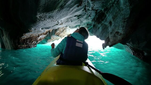 Woman paddles kayak in the Marble Cave in Chilean Patagonia and explores the intricate ceiling of the cave