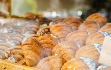 A variety of fresh pastries in the bakery window. Sweet big Croissant on shelf show for sale. Close up of appetizing golden croissants in cafe on shop window.