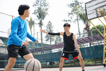 Two Asian Men Playing Basketball in a Court