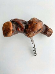 A corkscrew for wine bottles with a wooden handle made from grapevine.