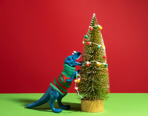 Happy dinosaur in knitted sweater decorates Christmas tree with retro bulb garland.