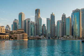 Obraz premium View of Dubai modern skyscrapers reflecting in the water of Burj Khalifa Lake during early evening, showcasing urban architecture and waterfront living, UAE