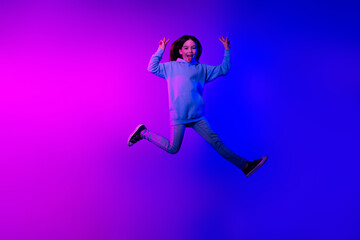 Full length photo of shiny attractive little lady dressed hoodie jumping high showing v-signs isolated neon pink color background