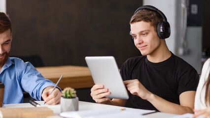 Internet surfing. Student using tablet in library, listening music in headphones, free space
